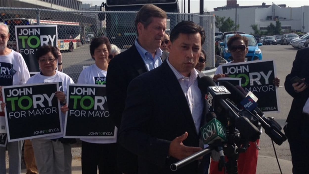 Le ministre provincial du Développement économique Brad Duguid appuie John Tory (arrière-plan).