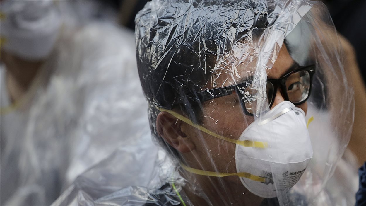 À Hong Kong, un manifestant pro-démocratie porte un masque et du plastique pour se protéger du poivre de Cayenne et des gaz lacrymogènes de la police.