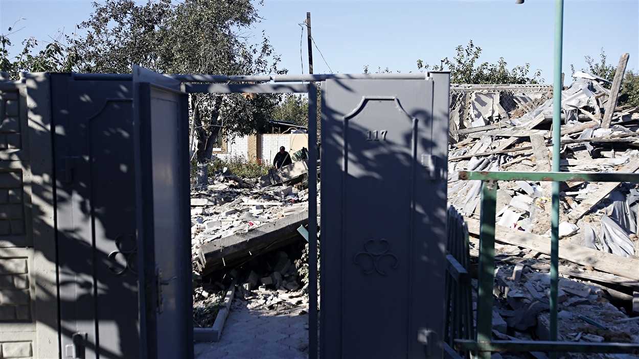Une femme observe une maison détruite lors d'un bombardement à Donetsk, en Ukraine.