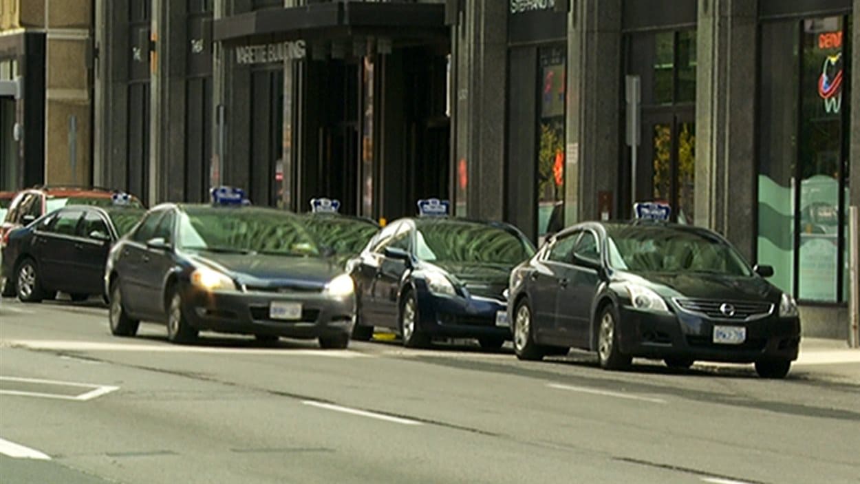 Des taxis sont stationnés et attendent des clients sur une rue d'Ottawa.