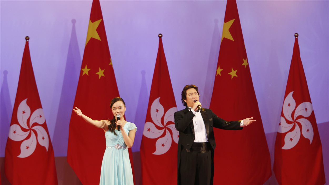 Des chanteurs s'exécutent devant les drapeaux de la Chine et de Hong Kong lors de célébration marquant la fête nationale chinoise.