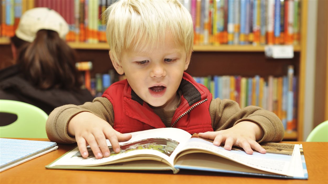 Jeune garçon lisant un livre à la bibliothèque.