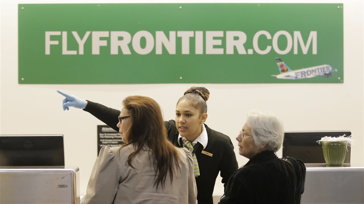 Une employée de Frontier Airlines à l'aéroport de Cleveland dirige des clients.