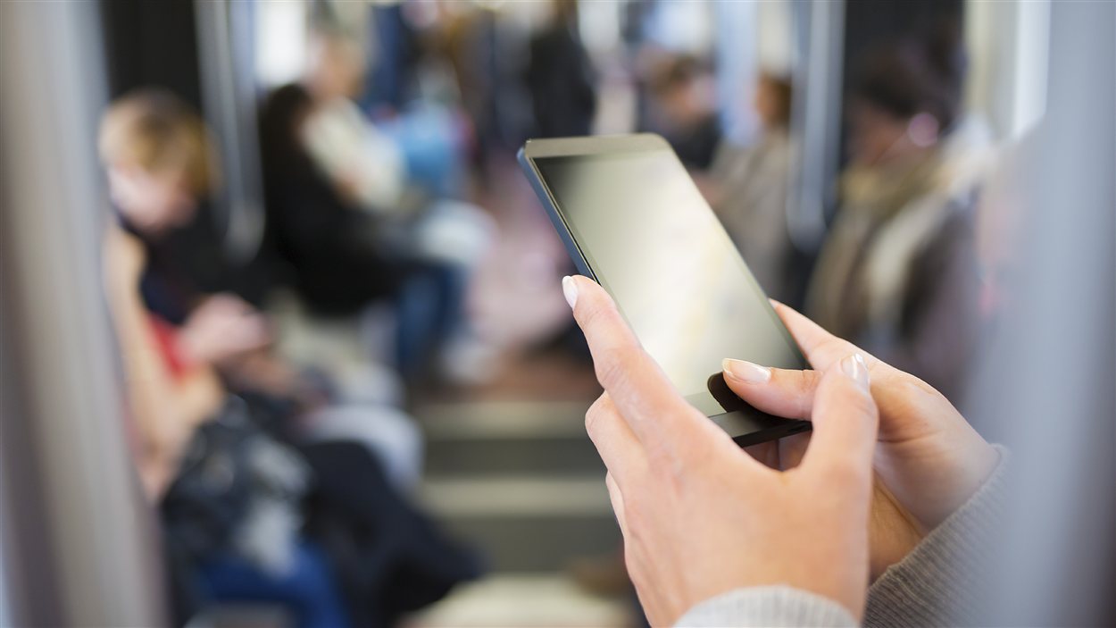 Une femme consulte son téléphone intelligent dans le métro