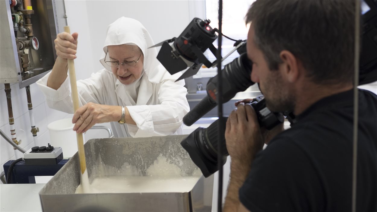 Soeur France mélange la pâte qui servira à fabriquer les hosties sous l'oeil attentif du caméraman