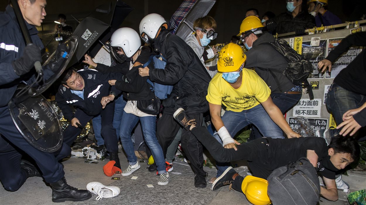 Des manifestants sont chassés par des policiers antiémeutes devant le parlement à Hong Kong, mercredi matin.