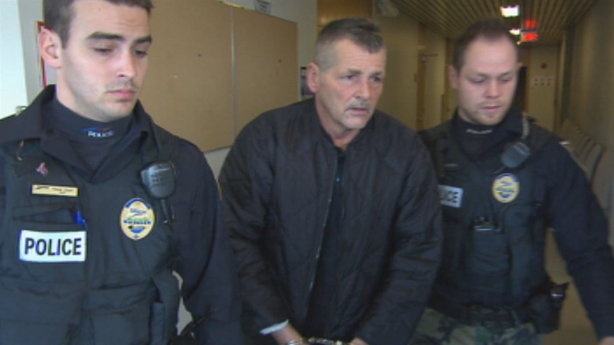 Roger Belley escorté par deux policiers au palais de justice de Chicoutimi