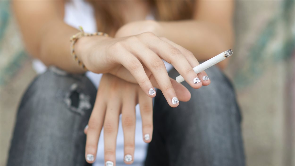Une adolescente fume une cigarette.