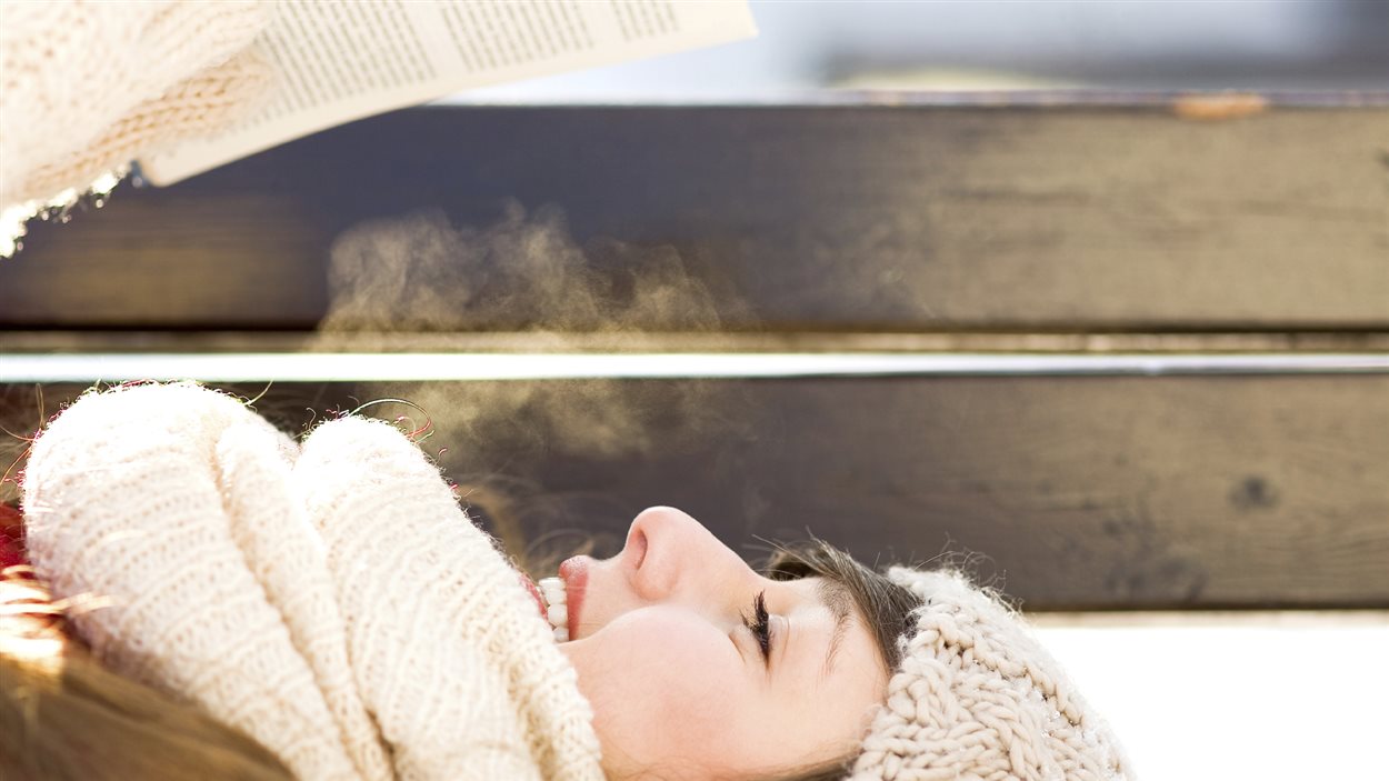 Femme lisant sur un banc en hiver