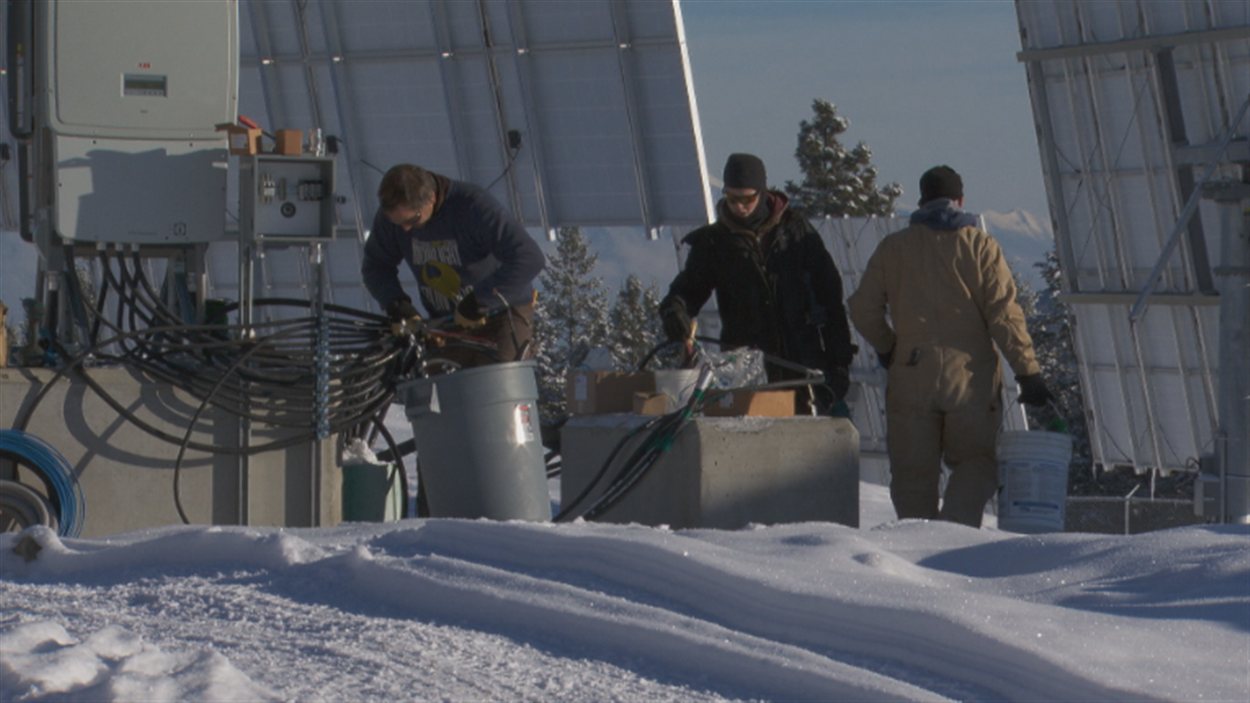 Des travailleurs branchent des fils électriques à la centrale solaire SunMine.