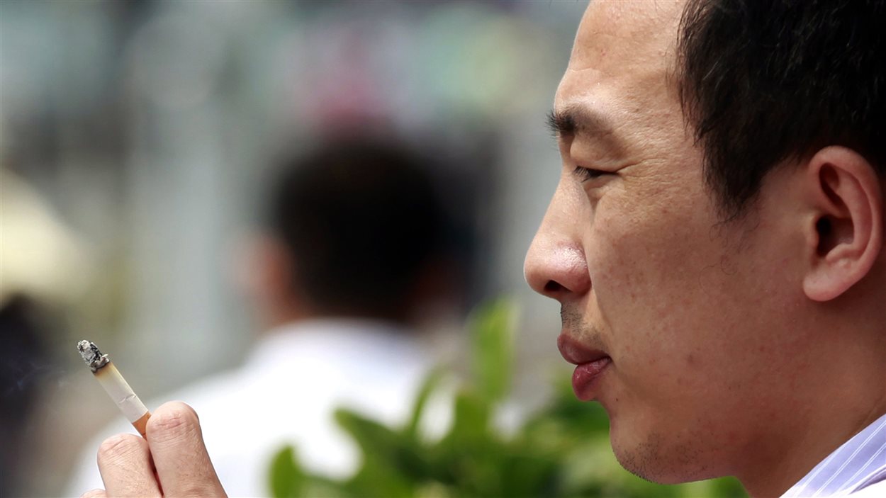 Un homme fume dans une zone désignée à Pékin, en Chine.