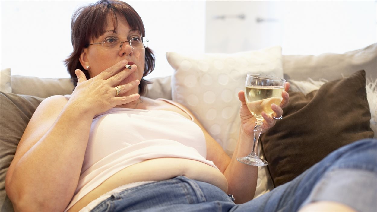 Une femme obèse boit et fume. 