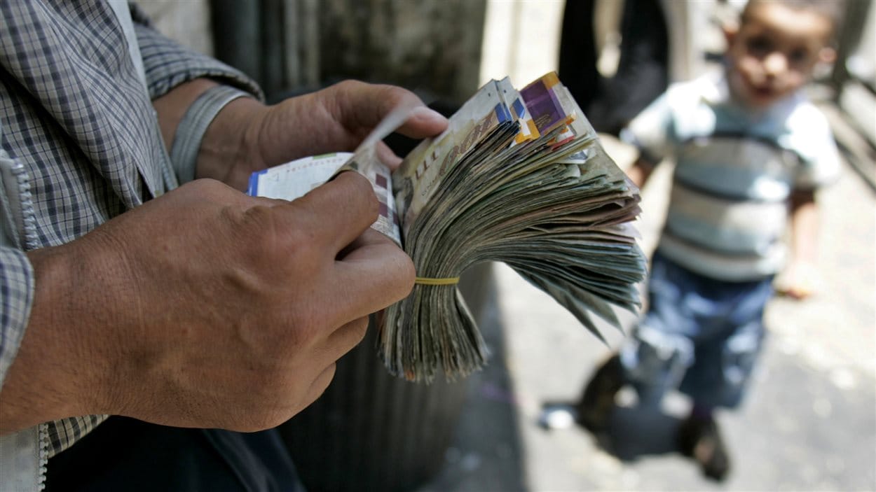 Un changeur palestinien compte ses billets dans une rue de Ramallah, en Cisjordanie.