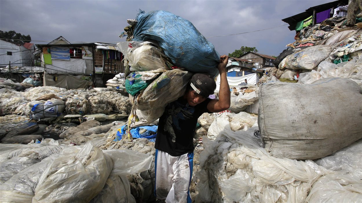 Dans un bidonville de Manille, aux Philippines, un homme transporte des déchets pour aller les vendre.