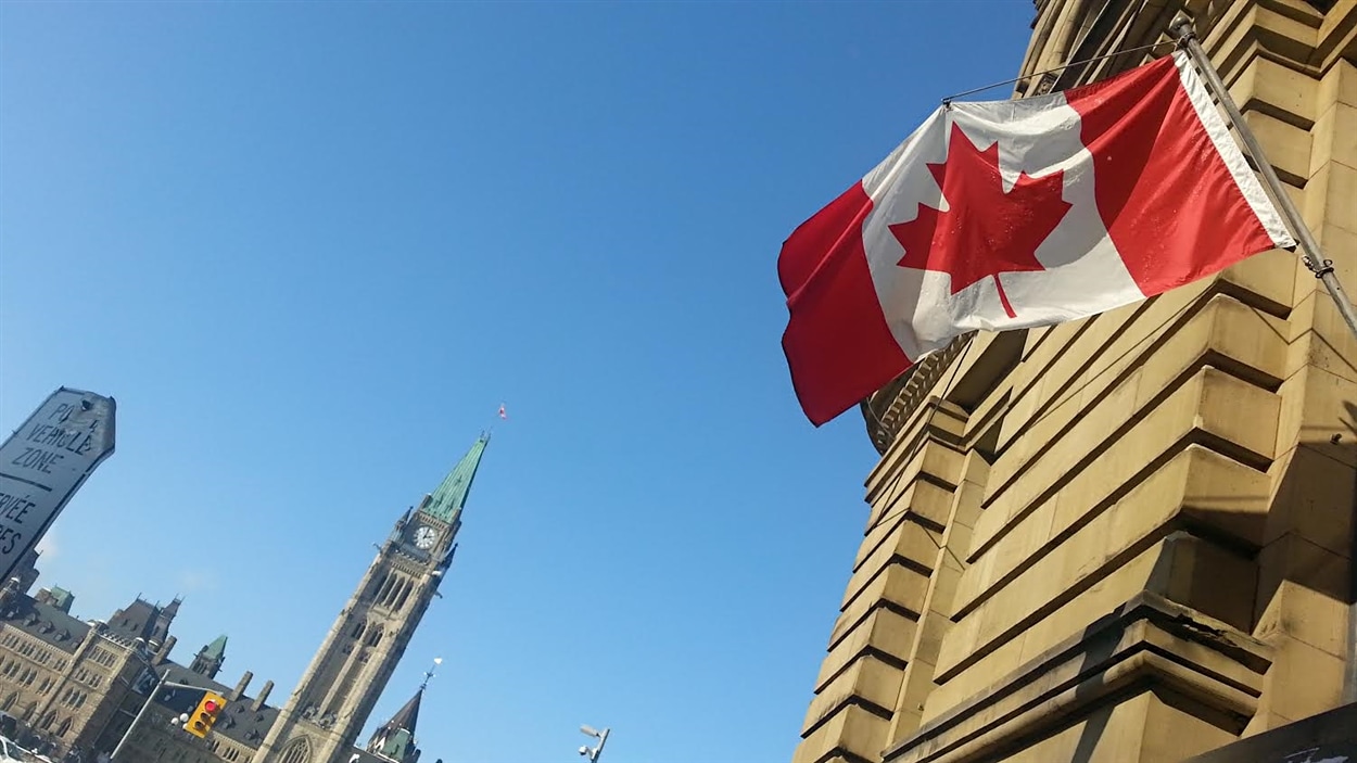 Le drapeau canadien flotte sur un édifice devant la colline du Parlement, à Ottawa, le 6 février 2015.