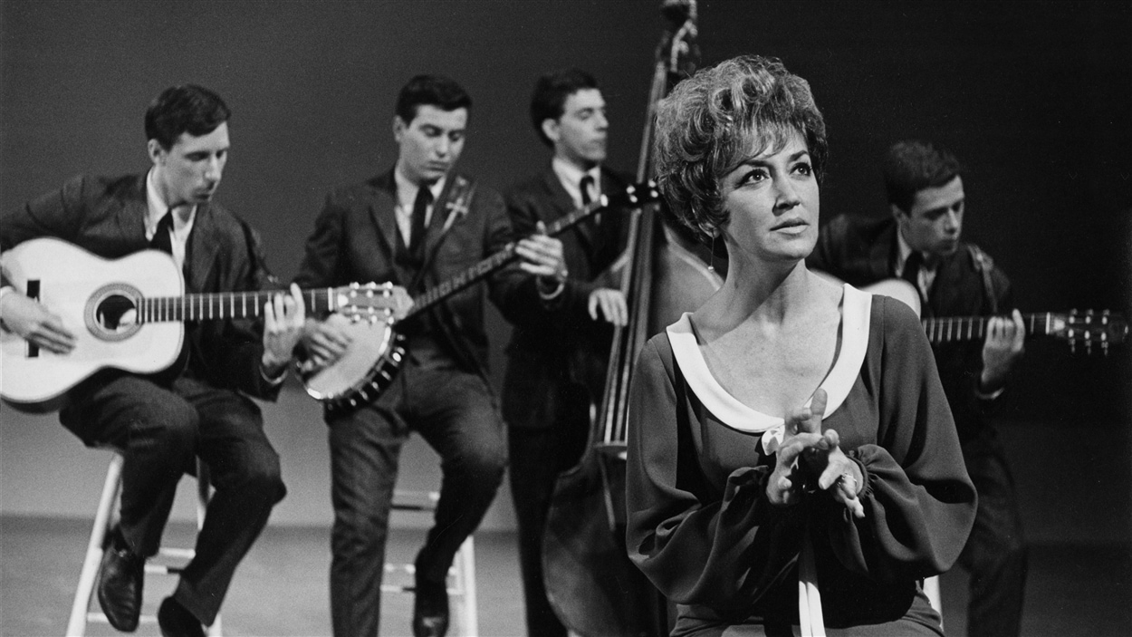 La chanteuse Lucille Dumont durant une prestation accompagnée par les musiciens du groupe les Quatre-Vingts, en 1965.