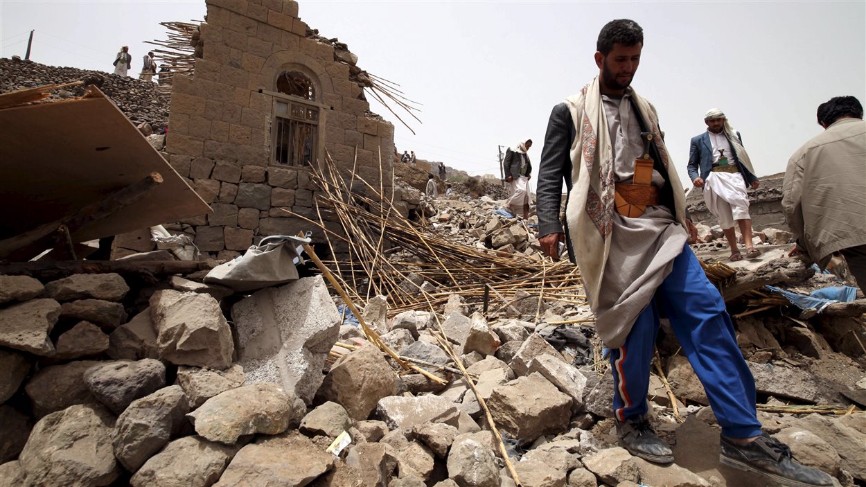 Des résidents sur les décombres de maisons détruites par une frappe aérienne dans un village près de Sanaa.