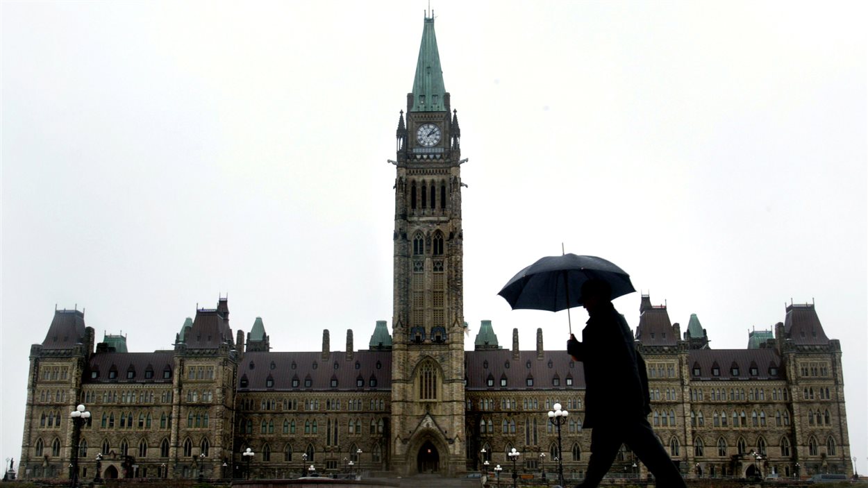 Un homme marche devant le l'hôtel du Parlement à Ottawa.