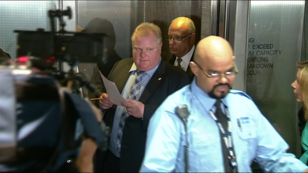 Un agent de sécurité ouvre la voie à l'ex-maire Rob Ford face à une meute de journalistes (archives). 
