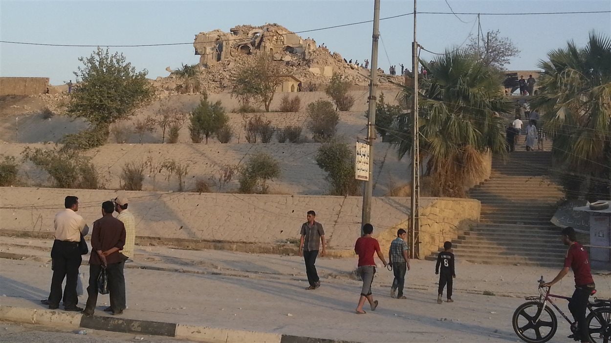 Des passants regardent les ruines de la Mosquée du prophète Jonas, à Mossoul.