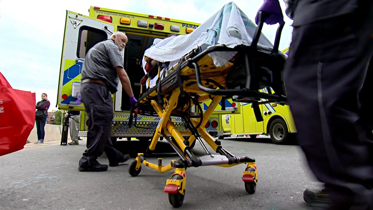 Des ambulanciers amènent un enfant sur une civière pour le déménager vers le Centre universitaire de santé McGill (CUSM).