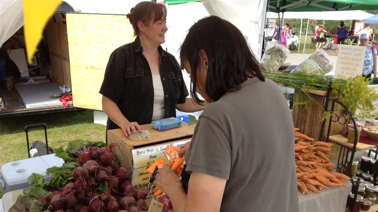 Une cliente achète des légumes d'une agricultrice