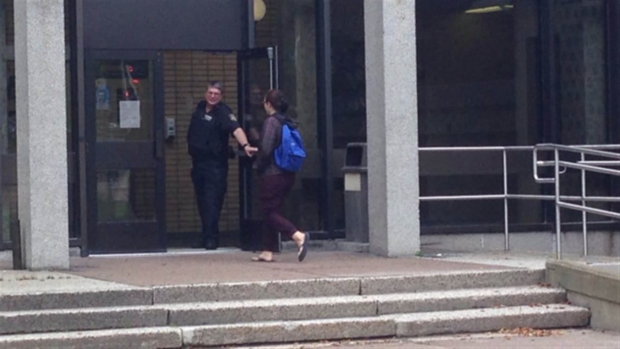 Un agent de sécurité ouvre la porte à une étudiante du département de médecine.