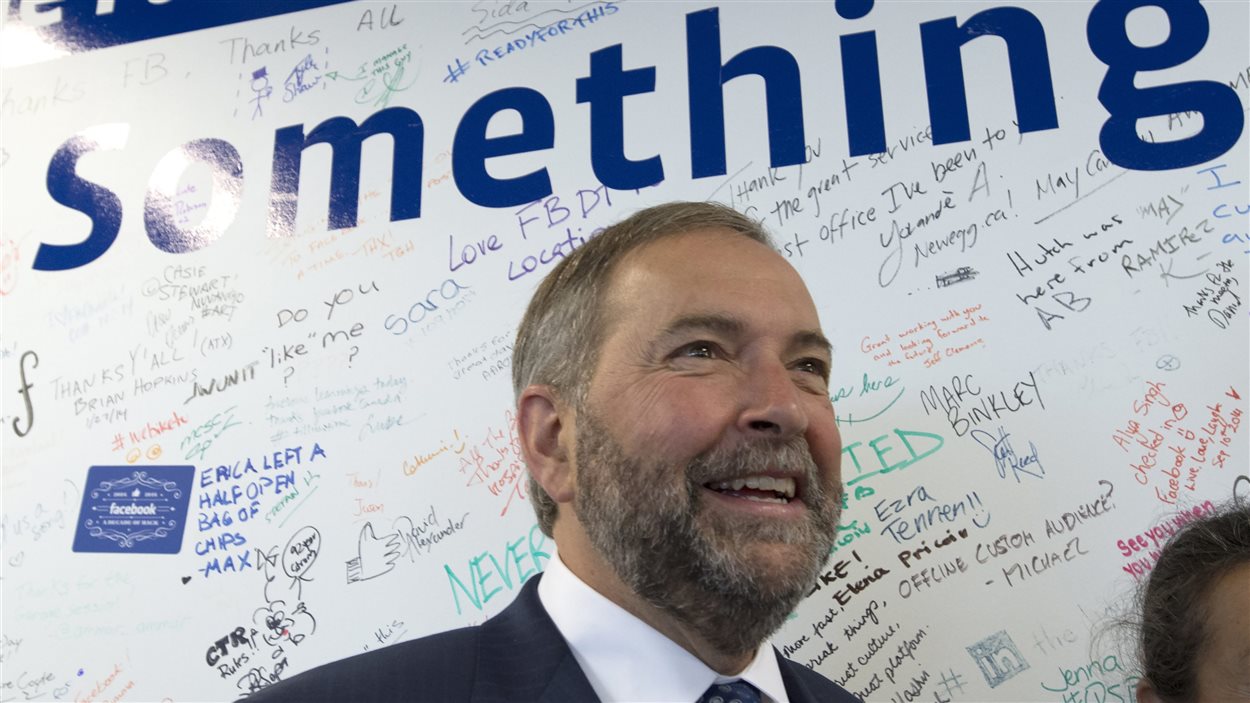 Thomas Mulcair sourit après avoir signé le mur de Facebook, à Toronto.