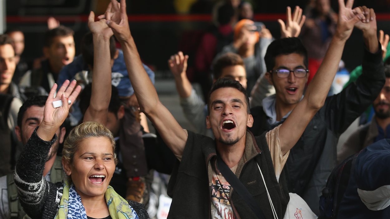 Des migrants arrivent à Munich, en Allemagne, et saluent la foule qui les applaudit.