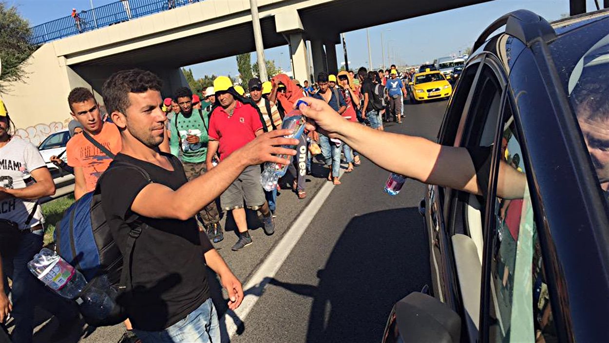De bons samaritains s'arrêtent pour donner de l'eau et des vivres aux migrants qui marchent vers l'Autriche.