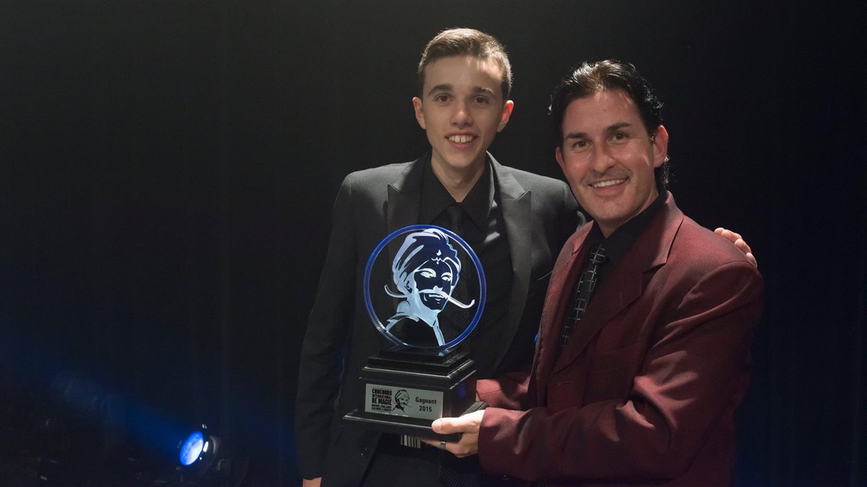 Philippe Thériault (à gauche) reçoit le grand prix du Concours international de magie de Québec, des mains du champion 2014, Michael Dardant. 