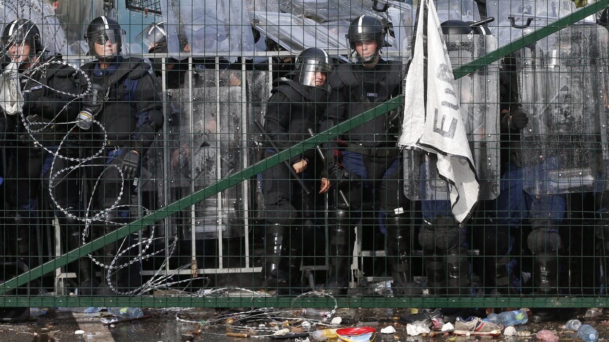 Derrière une clôture, la police hongroise surveille les migrants à la frontière avec la Serbie.