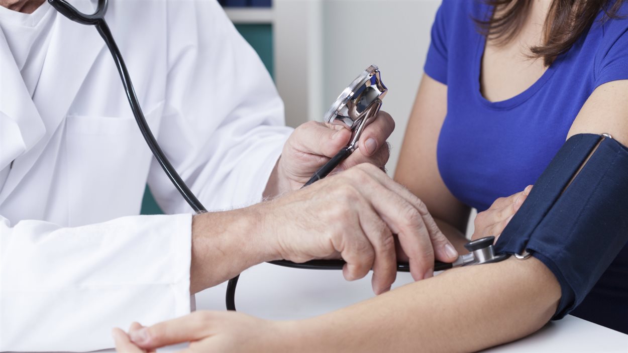 Un médecin mesure la pression artérielle d'une patiente.