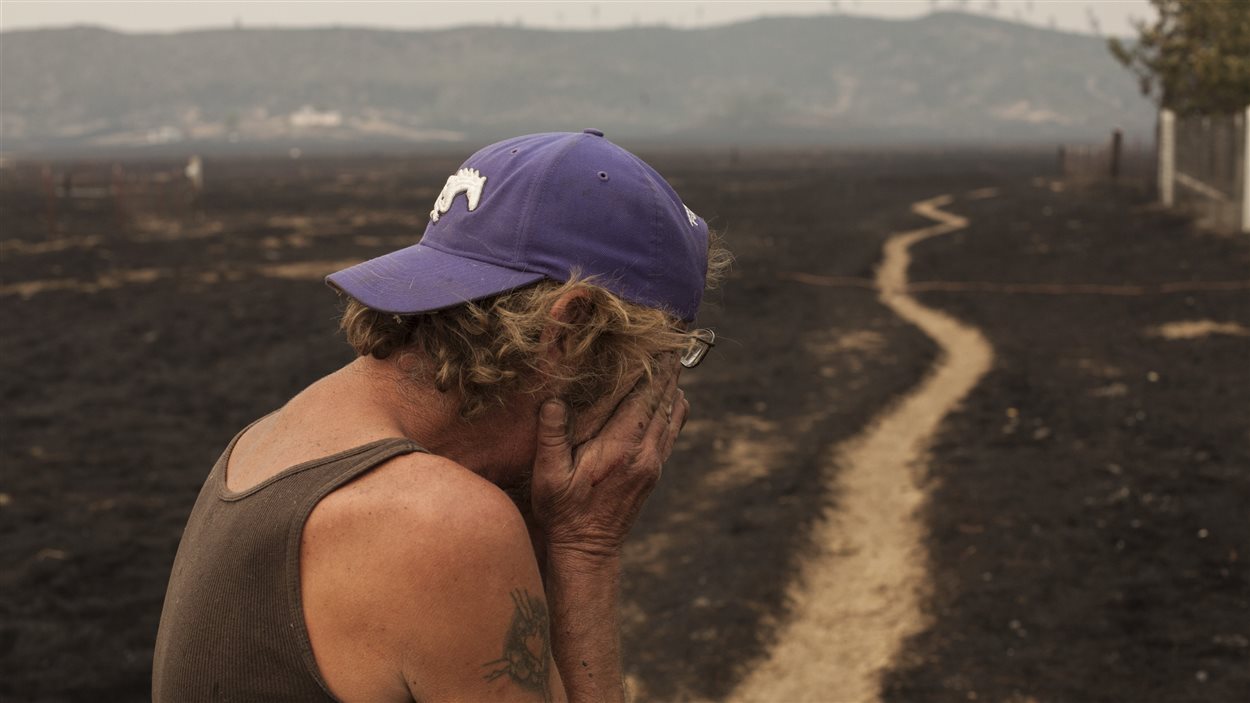 Robert Hooper, épuisé après plusieurs jours sans sommeil, est envahi par l'émotion en regardant sa propriété qui a été brûlée par l'incendie baptisé «Fire Valley», près de Middleton, en Californie, une zone frappée par la sécheresse.