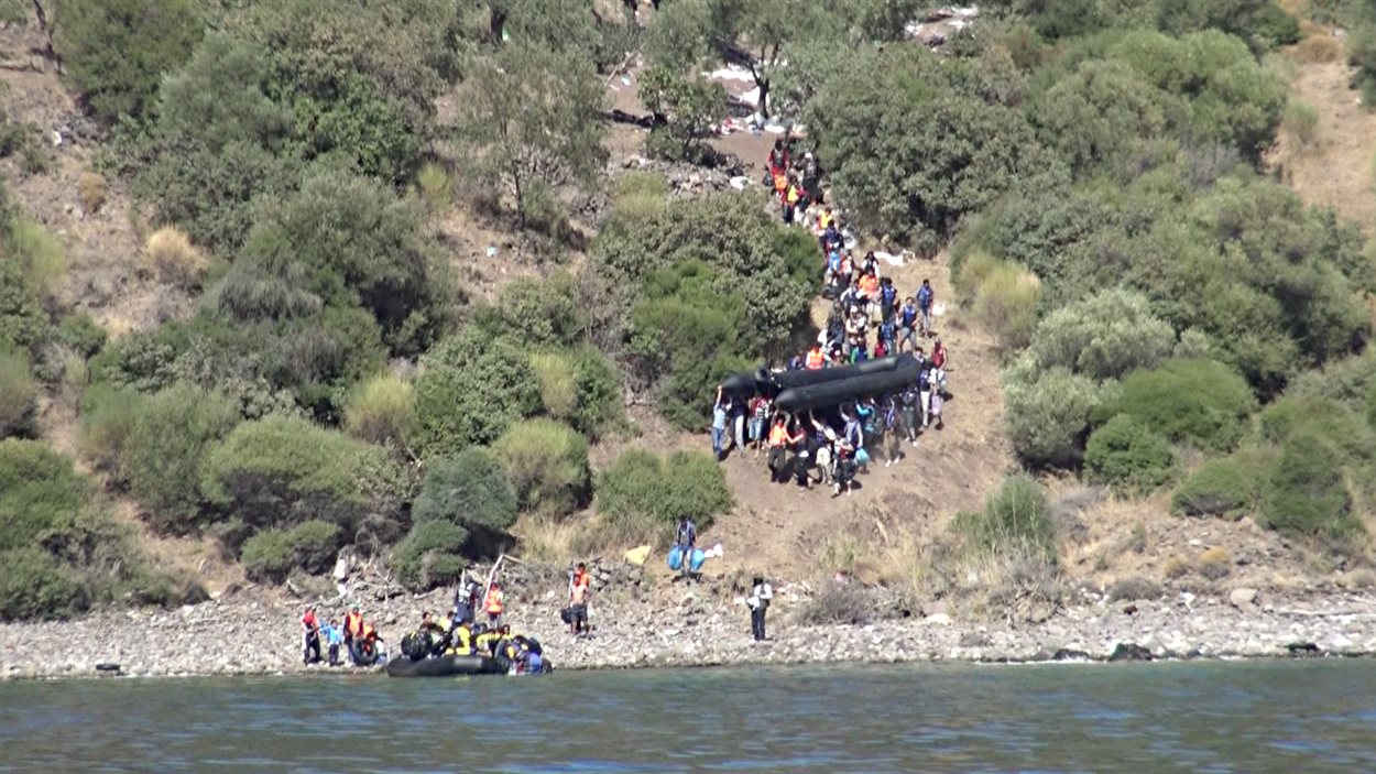 Des migrants sur une côte turque s'approchent de la rive pour mettre les bateaux à l'eau.