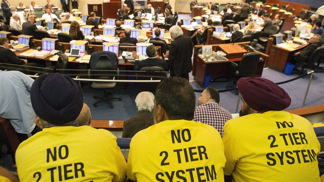 Des chauffeurs de taxi portent un t-shirt jaune anti-Uber, lors de la réunion du conseil municipal à Toronto, mercredi