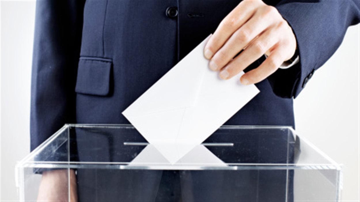 Un homme dépose son vote dans une urne de scrutin.