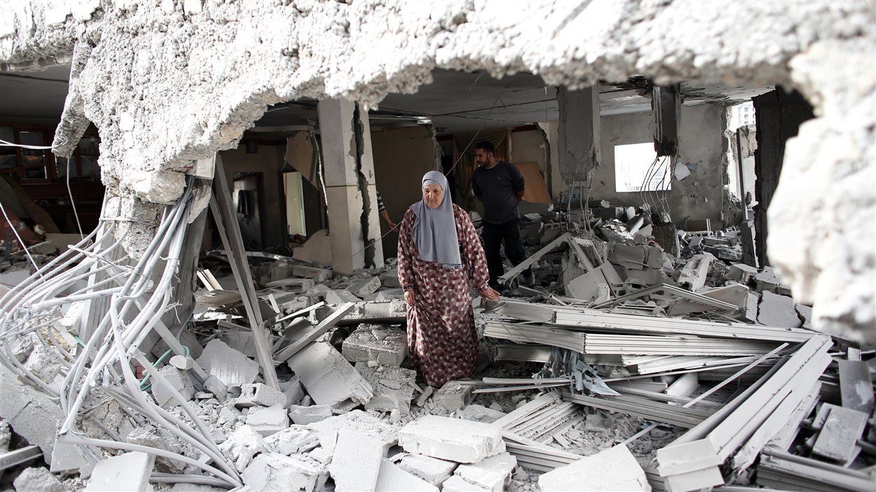 Une Palestinienne tente de se frayer un chemin dans les décombres d'une des deux maisons détruites mardi par Israël.