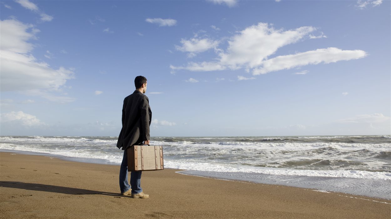 Un homme sur le bord de la mer avec une valise à la main