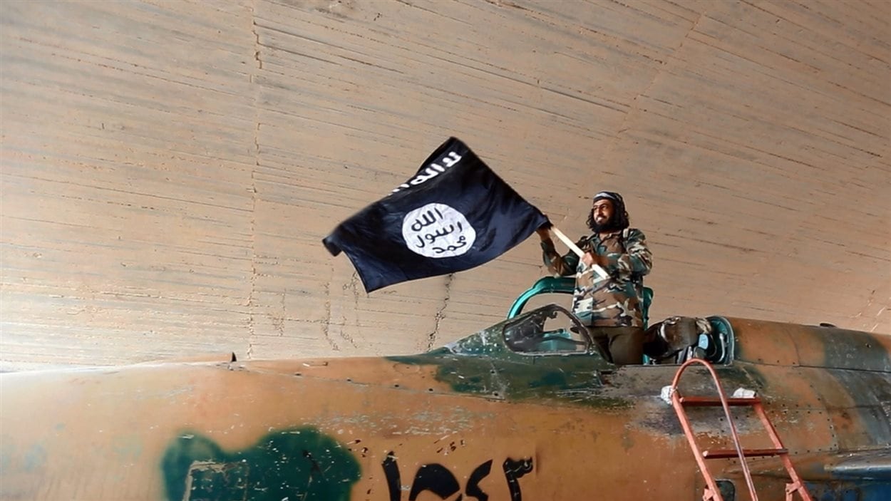 Un combattant brandit le drapeau du groupe armé État islamique.