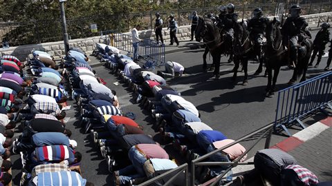 Des Palestiniens prient dans les rues de Jérusalem-Est, sous le regard de policiers israéliens. La police interdit aux hommes de 40 ans de se rendre à la mosquée Al-Aqsa, considéré comme le troisième lieu saint de l'islam.