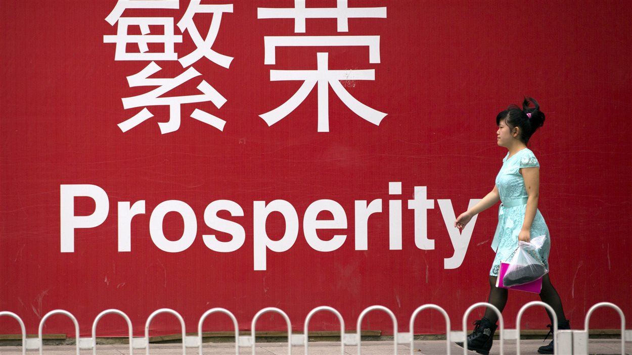 Une femme à Pékin marche devant une pancarte sur laquelle est écrit le mot « Prospérité ».