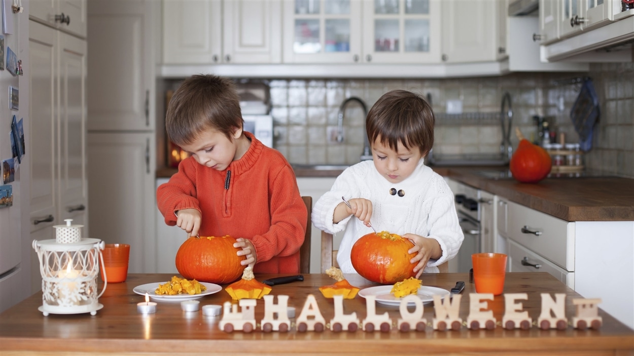 Deux enfants préparent des citrouilles pour l'Halloween.