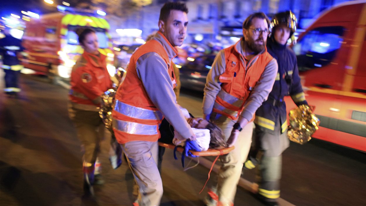 Les ambulanciers évacuent une femme du théâtre Bataclan à Paris.