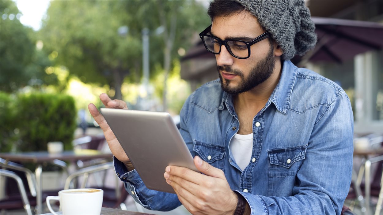 Un jeune homme avec sa tablette électronique dans un café