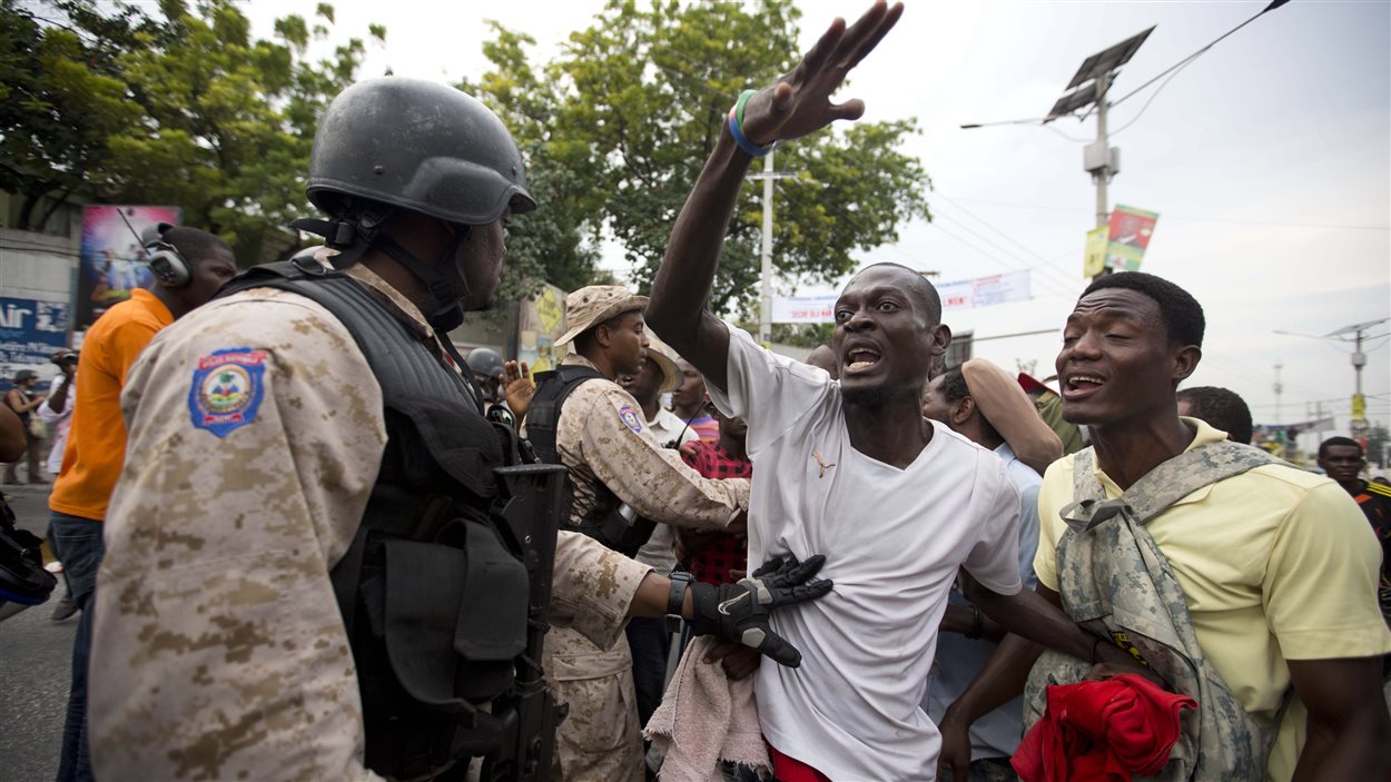 Un officier des forces de l'ordre haitiennes tente de retenir un manifestant le 26 novembre à Port-au-Prince