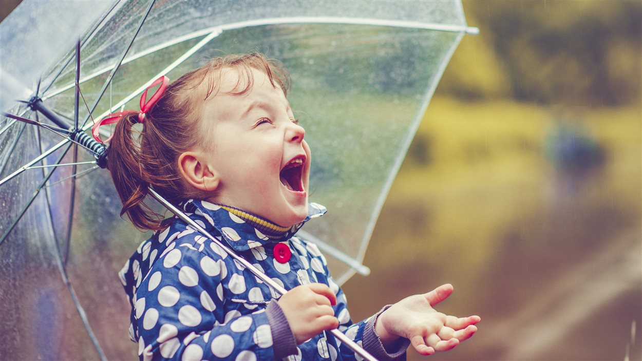 Un enfant rit sous la pluie.