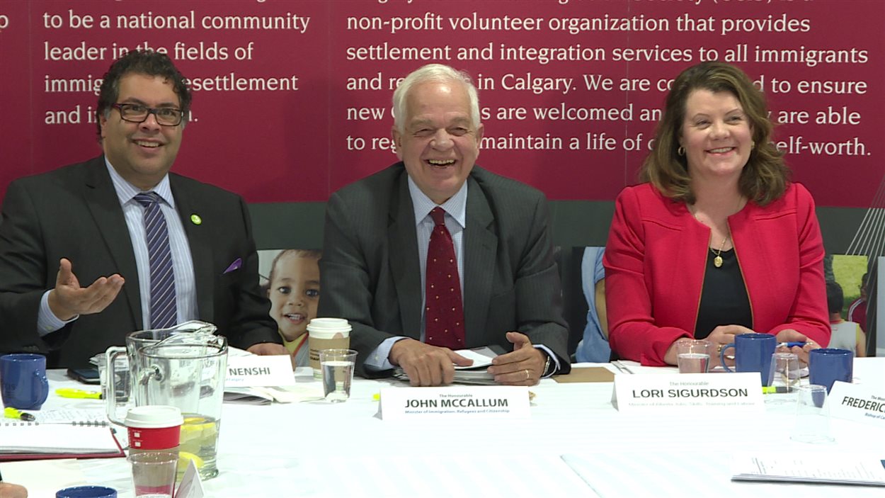 Le ministre de l'Immigration, des Réfugiés et de la Citoyenneté du Canada, John McCallum entouré du maire de Calgary, Naheed Nenshi et de la ministre albertaine de l'Emploi, des Compétences, de la Formation et du Travail, Lori Sigurdson.
