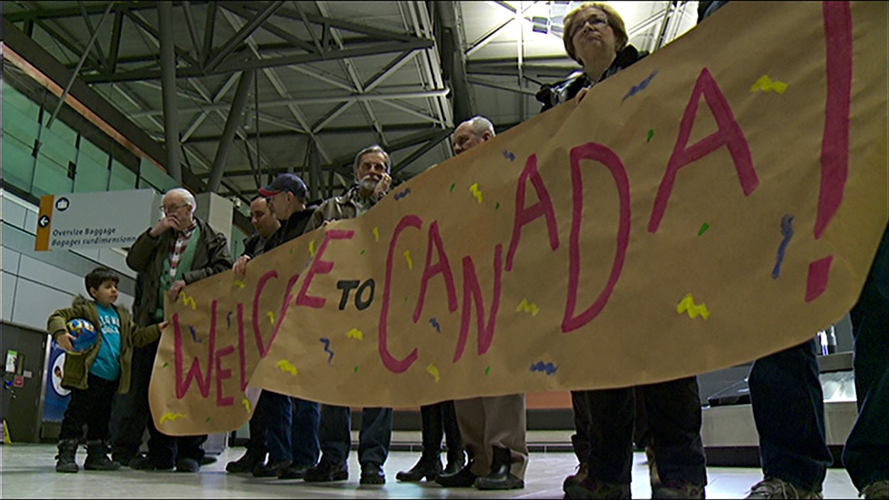 Des citoyens en train d'accueillir des réfugiés à l'aéroport d'Ottawa.