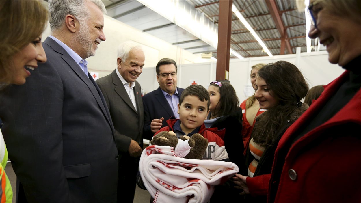 Une famille syrienne est accueillie à Montréal par le premier ministre Philippe Couillard, le ministre fédéral de l'Immigration John McCallum, le maire de Montréal, Denis Coderre, et la ministre fédérale du Patrimoine, Mélanie Joly.